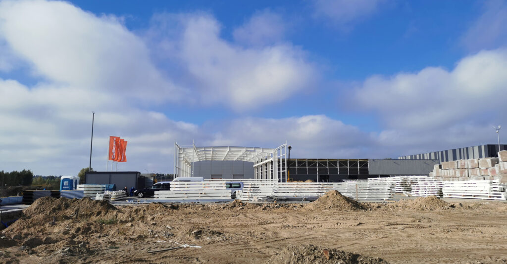 widok na konstrukcje hali mechaników i rozbudowywaną halę - inwestycja dla producenta okien PVC, AdamS, w Mrągowie, woj. warmińsko-mazurskie, budowa CoBouw Polska