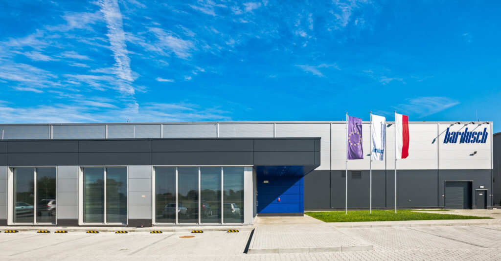 obiekt widziany od frontu - hala produkcyjno-magazynowa wraz z budynkiem socjalno-biurowym, pralnia przemysłowa, dla Bardusch Polska
