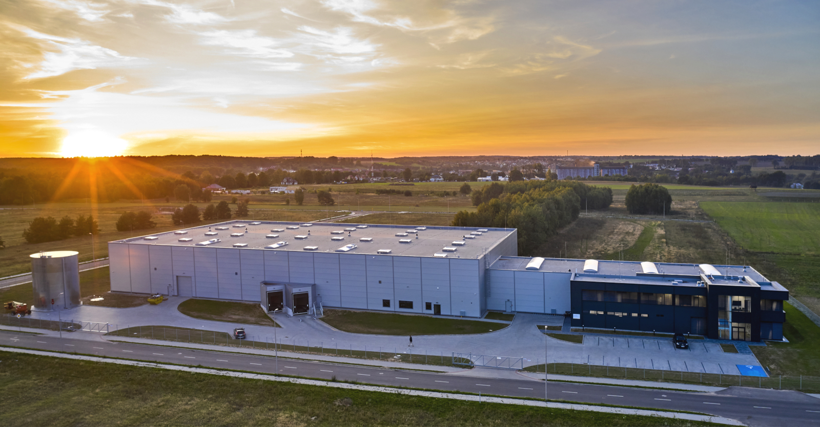 hala Kentaur o zachodzie słońca - nowoczeny obiekt przemysłowy, z budynkiem biurowym, dla firmy Kentaur Production, wybudowany pod klucz, w Łobzie, w woj. zachodniopomorskim
