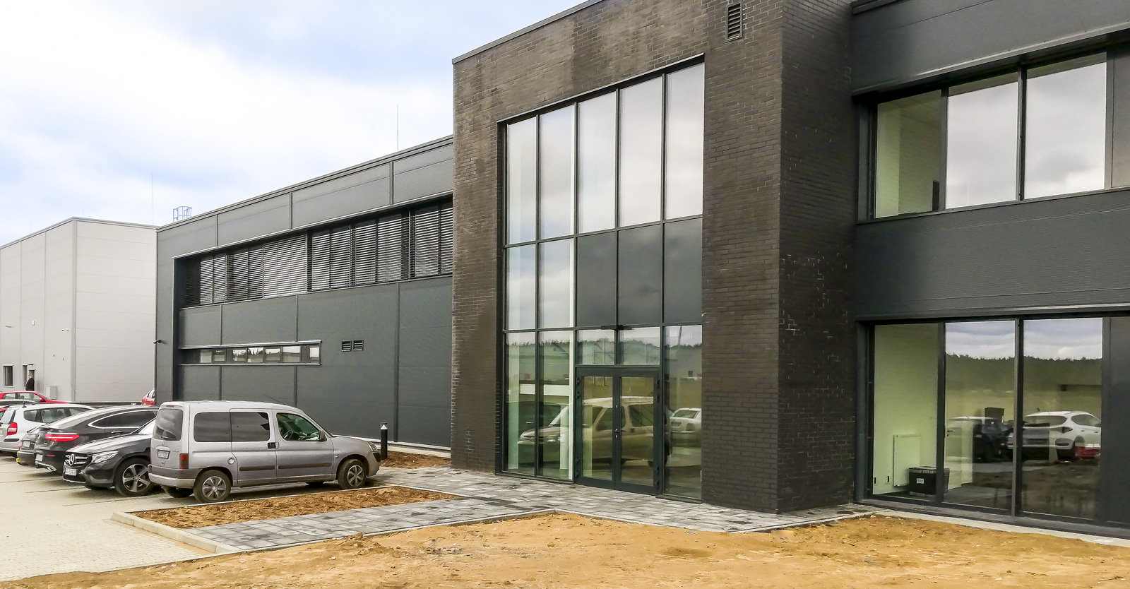 widok obiektu od strony budynku biurowego - hala dla Kentaur Production, producenta odzieży roboczej, z Łobza, w woj. zachodniopomorskim